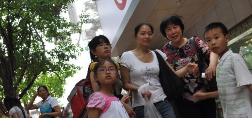 Grupka 5 osób przygląda się z zainteresowaniem osobom rozmawiającym na ulicy przed bankiem w Chinach