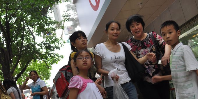 Grupka 5 osób przygląda się z zainteresowaniem osobom rozmawiającym na ulicy przed bankiem w Chinach